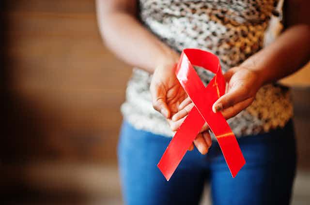 Black woman holding AIDS ribbon.