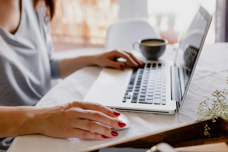 A woman's hands are seen as she looks at her laptop.
