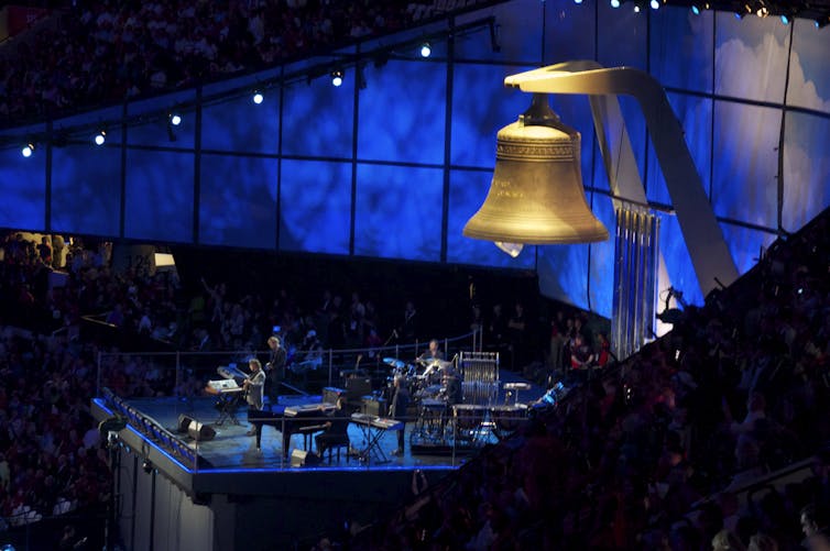 A giant bell hangs above a blue stage.