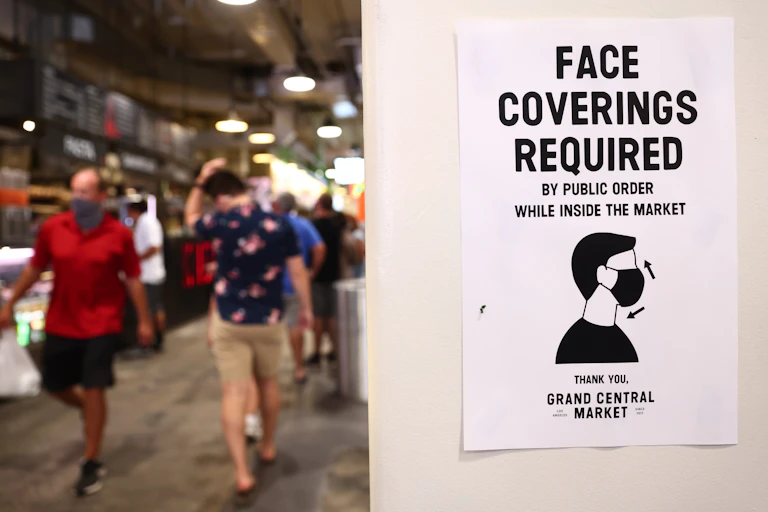 a sign requiring face coverings in a busy indoor market