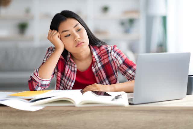 Teenage woman looking bored as she watches a lesson online