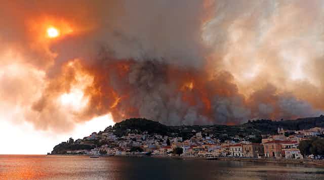 thick smoke blocks the sun over a coastal village