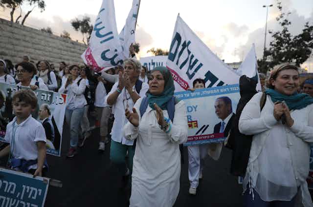 Women marching with banners in Arabic and Hebrew
