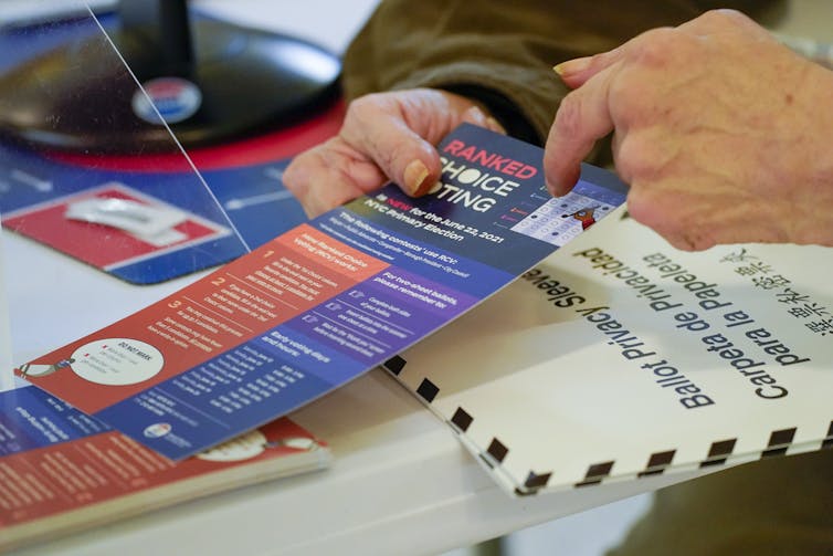 A person points at an information card labeled 'ranked-choice voting.'