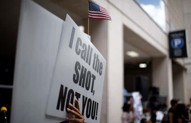 Anti-vaccine rally protesters hold signs outside of Houston Methodist Hospital in Houston, Texas, saying 'I call the shot, not you!.