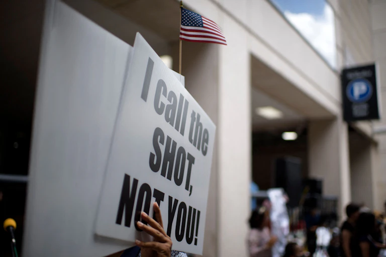 Anti-vaccine rally protesters hold signs outside of Houston Methodist Hospital in Houston, Texas, saying 'I call the shot, not you!.