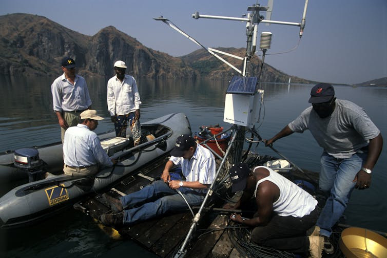 people on small boat and raft setting up scientific equipment
