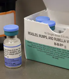 A vial of MMR vaccine next to a box of vials.