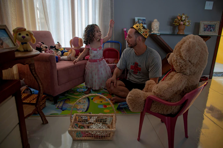 Father plays on living room floor with toddler daughter.
