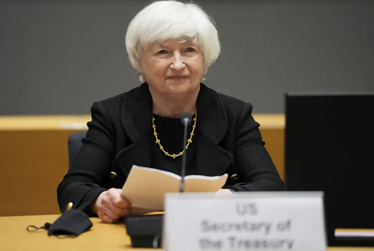 Janet Yellen duduk di meja sambil memegang salinan pidato di tangannya