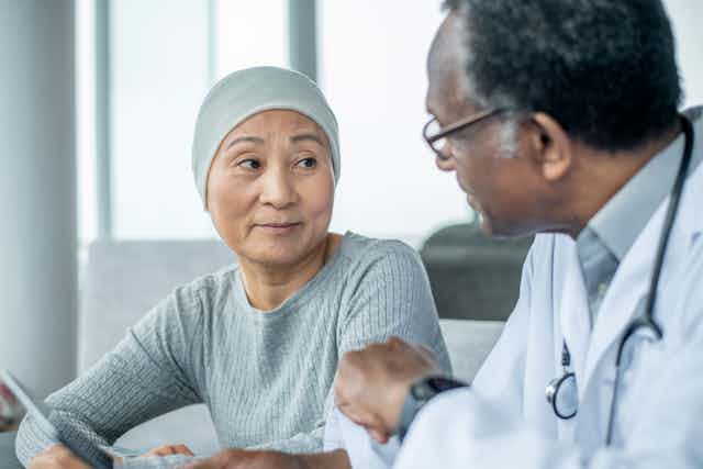 A woman with cancer is talking with her oncologist at the doctor's office.