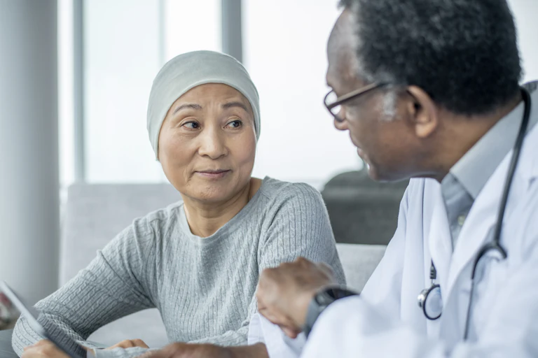 A woman with cancer is talking with her oncologist at the doctor's office.