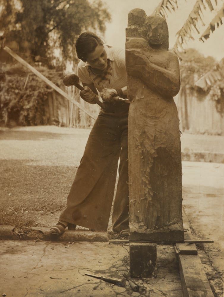 woman making large wooden sculpture