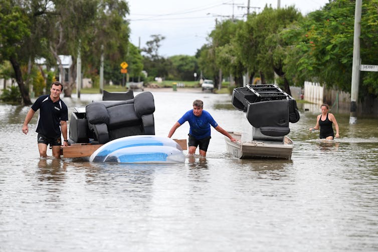 Men float furniture through floodwaters