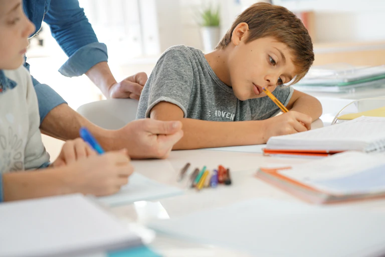 Young school student writing in class