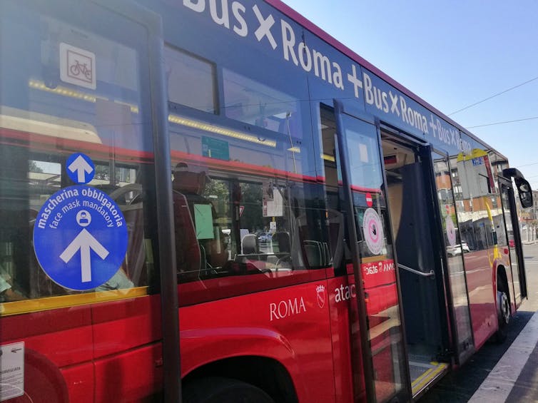 A sign requiring a mask and rear door entry on a public bus