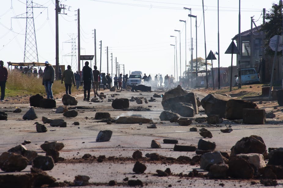 Rocks lie in the road, which is lined by electricity pylons and street light poles