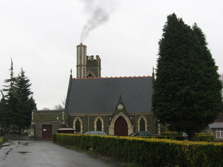 A church with crematorium behind, out of which smoke is issuing