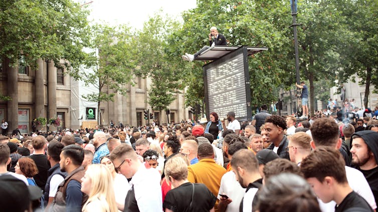 Crowded street scene with no social distancing.
