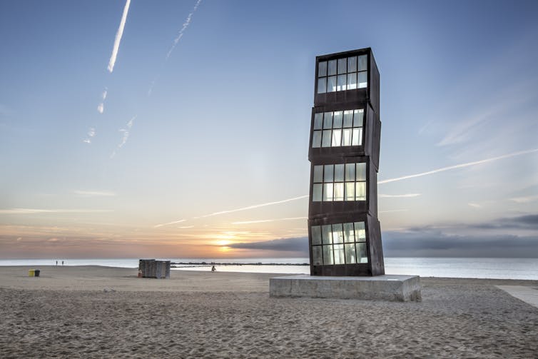 A large steel and glass sculpture on a beach in Barcelona