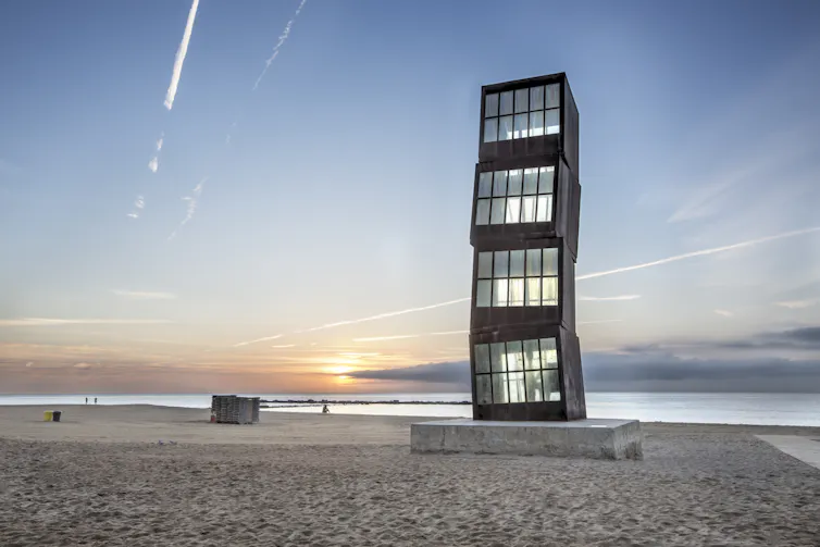 A large steel and glass sculpture on a beach in Barcelona