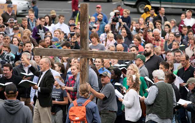 A large wooden cross is surrounded by members of Christ Church reading a psalm.