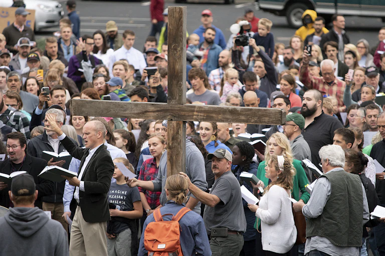 A large wooden cross is surrounded by members of Christ Church reading a psalm.