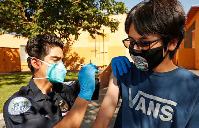 EMT gives COVID-19 vaccine shot to teenage boy