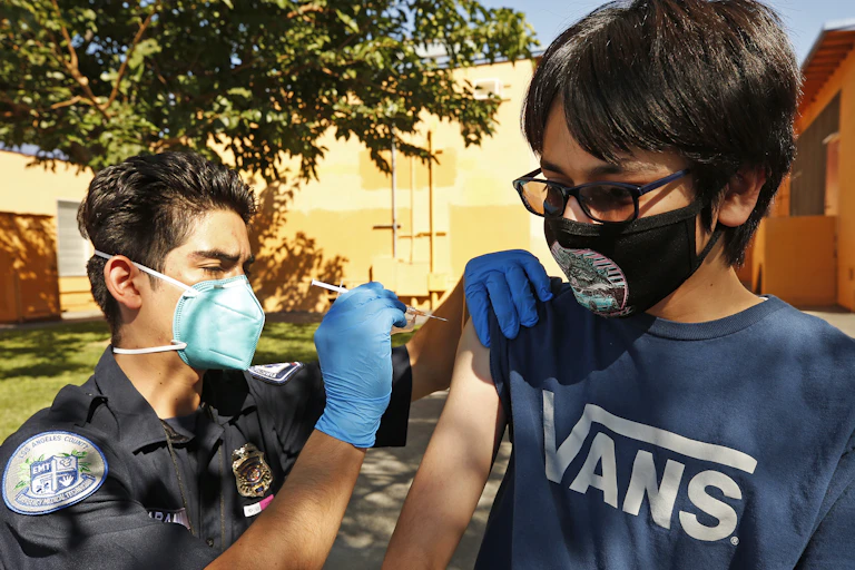 EMT gives COVID-19 vaccine shot to teenage boy