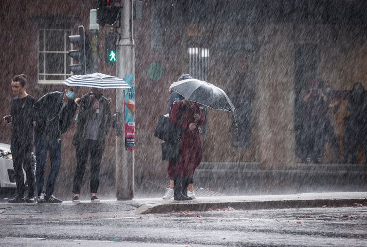 people queue in heavy rain