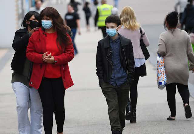 People in masks walking down a British street