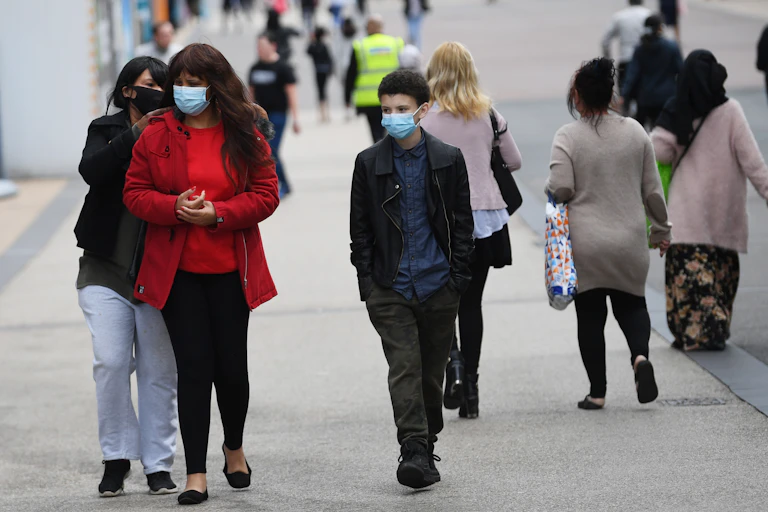 People in masks walking down a British street