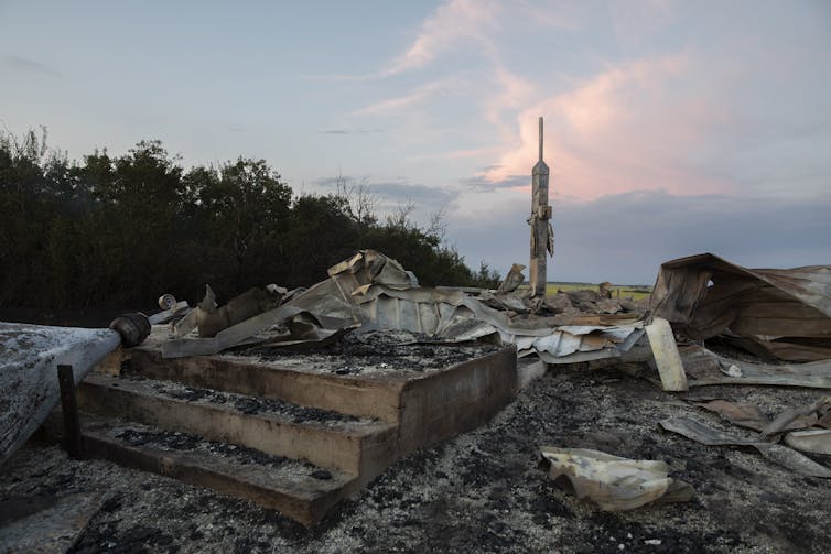 Ashes and debris are all that remains after a fire at a church in Saskatchewan. Debris with sunset in the background