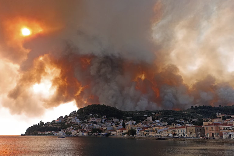 une épaisse fumée bloque le soleil au-dessus d'un village côtier