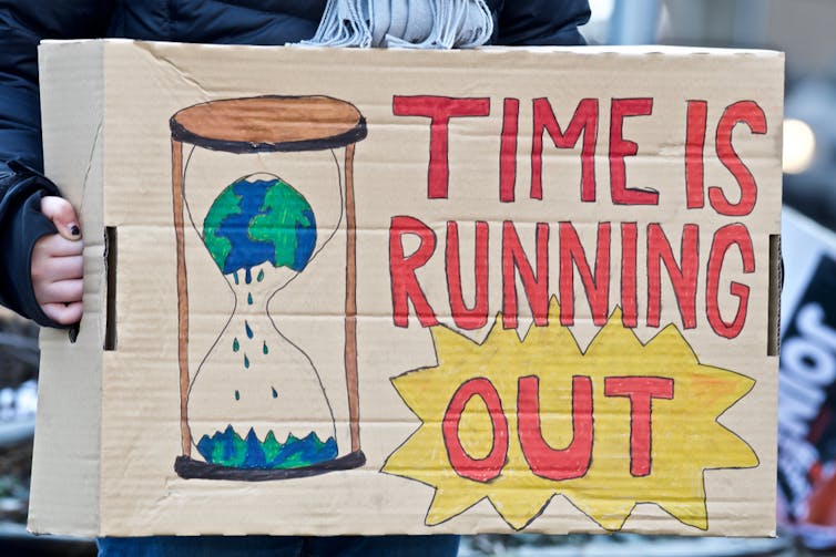 A home made protest placard showing the world inside an egg timer with the words 'time is running out'.