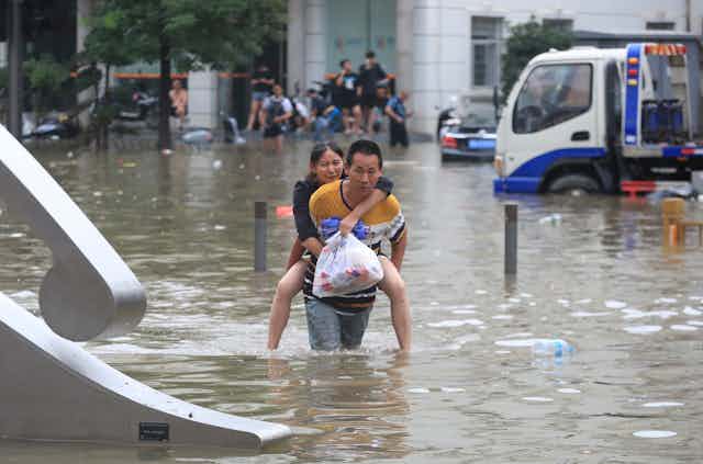 A man carries a woman through floodwaters in China