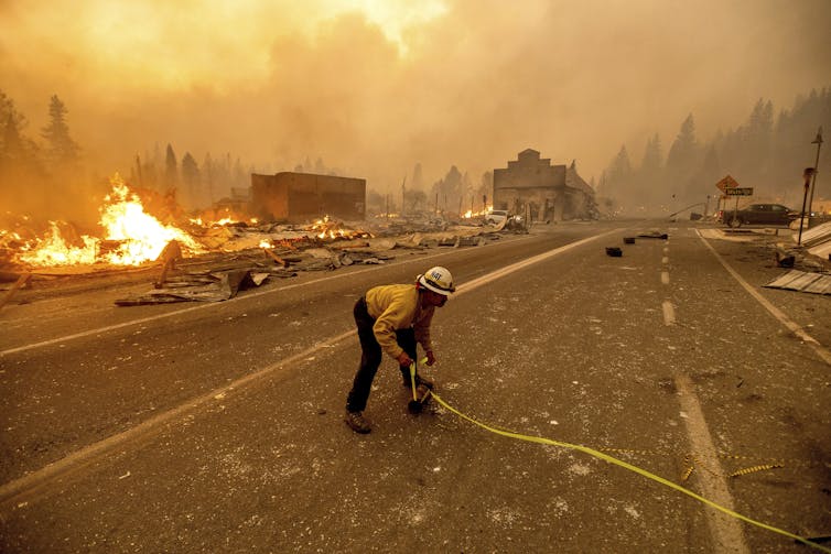 A fireman holding a hose on a smoke-filled road