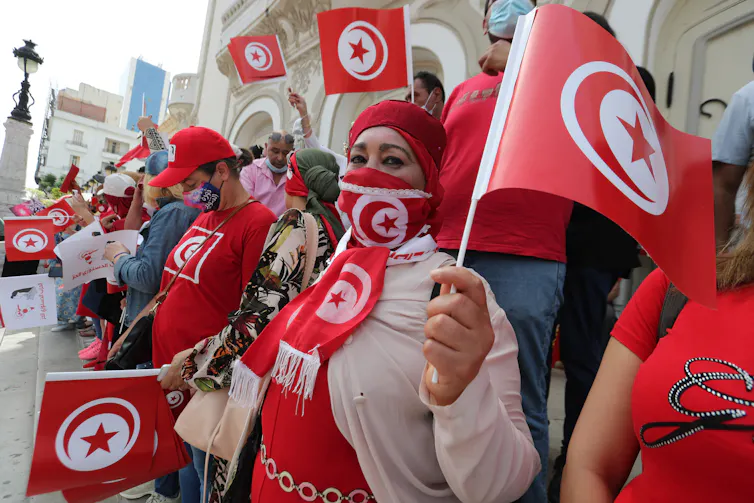 Supporters of Tunisia's Free Constitutional Party wearing read and waving the Tunisian flag on the streets of Tunis, July 2021.