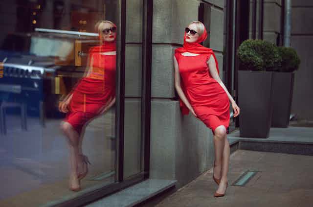 Mujer con vestido rojo mirando su reflejo en un escaparate