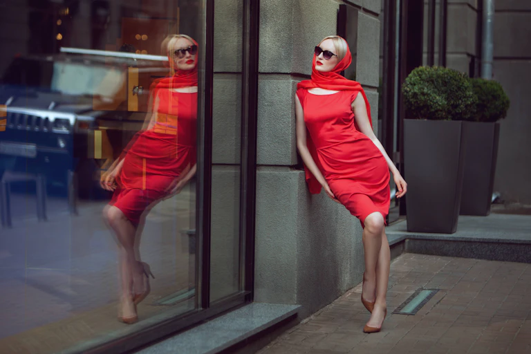 Mujer con vestido rojo mirando su reflejo en un escaparate