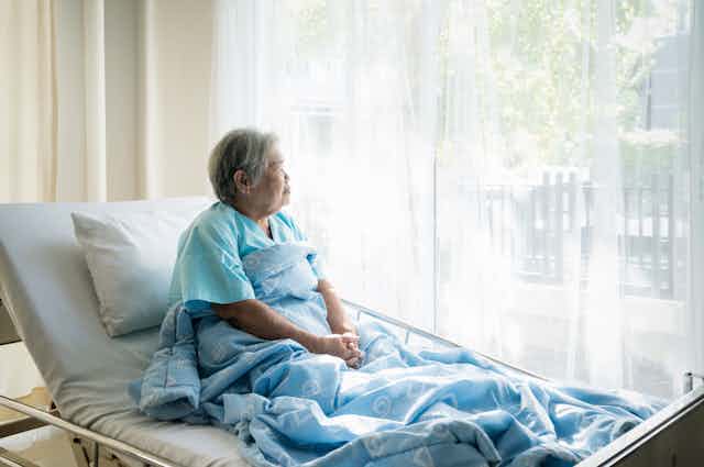 Patient sitting up in hospital bed, looking out of the window