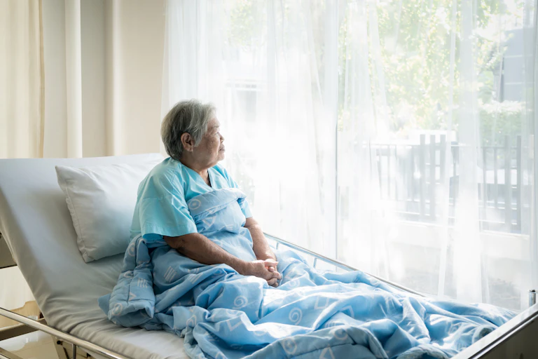 Patient sitting up in hospital bed, looking out of the window