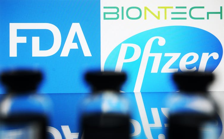 Vaccine vials lined up in front of the FDA and Pfizer BioNTech logos