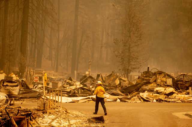 A firefighter walks through the charred rubble of town