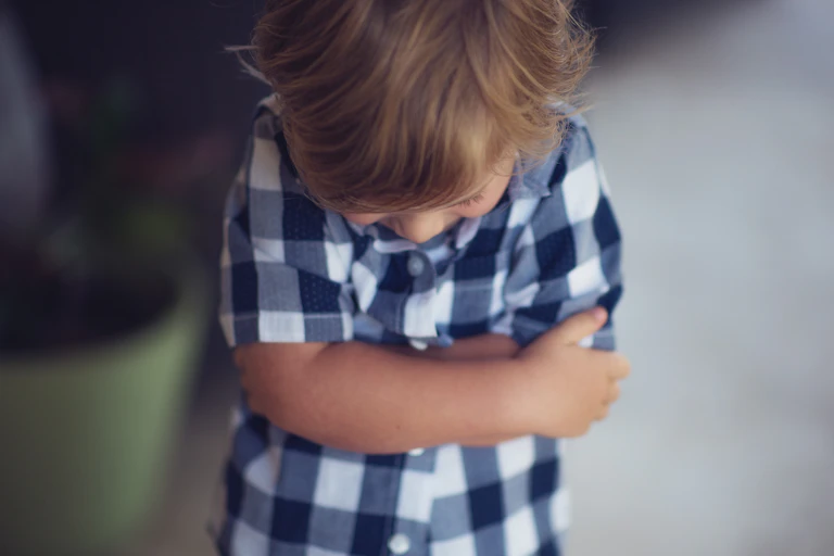 Little boy cross arms and looks at floor