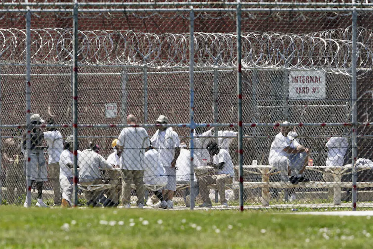 Prisoners populate a yard surrounded by razor wire.