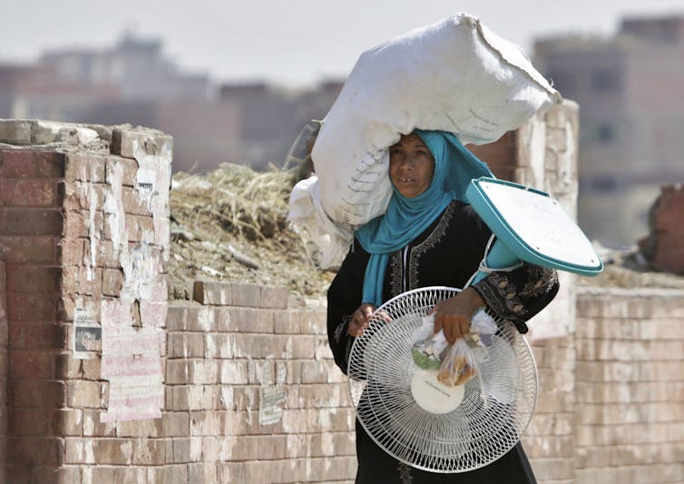 woman carries fan and sack