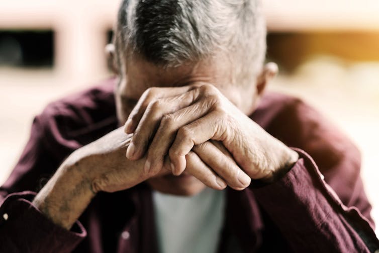 A man rests his head on his hands.