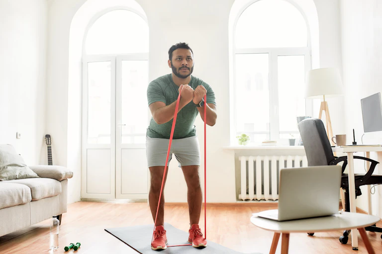 A man does bicep curls at home with resistance bands.