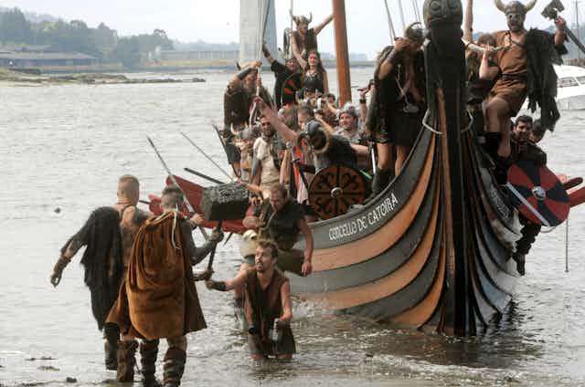 Men and women dressed as Vikings in a replica longship.